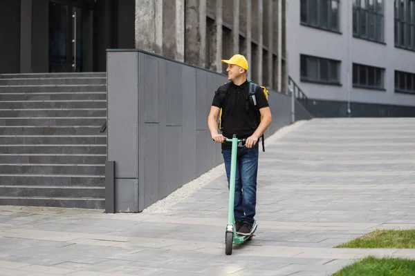 Homem mensageiro em scooter nas ruas da cidade com entrega de comida quente de takeaways e restaurantes para casa — Fotografia de Stock