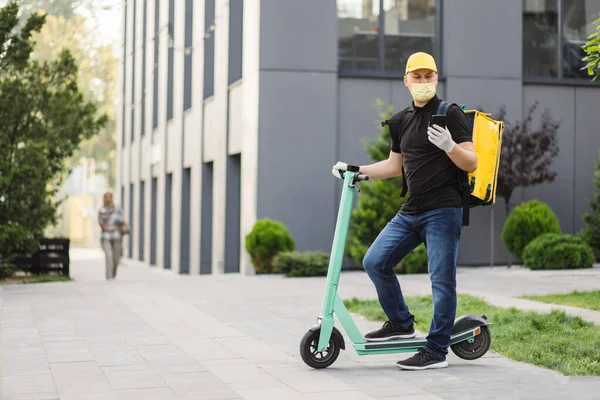 Delivery guy wearing facial mask working during covid-19 pandemic with backpack. — Fotografia de Stock