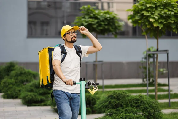 Dağıtım elemanı sarı şapkalı, motosikletli yolda gidiyor..