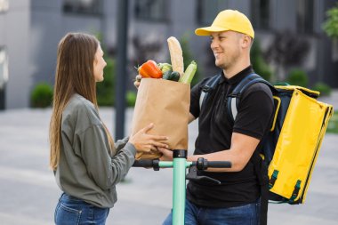 Beyaz üniformalı akıllı servis elemanı alıcıya taze yiyecek veriyor.