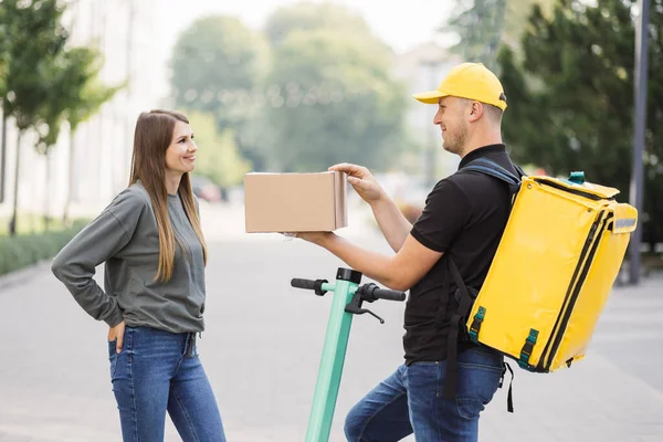 Kafkasyalı çekici kurye, beyaz kız müşterilere karton kutular getiriyor..