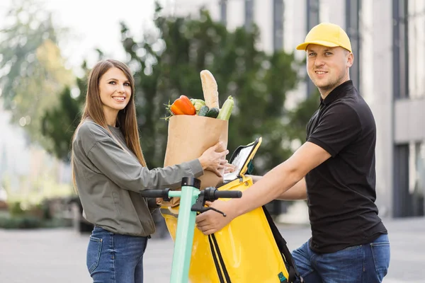 Beyaz kadın müşteri marketten yemek siparişiyle birlikte kağıt eko poşet getiriyor.