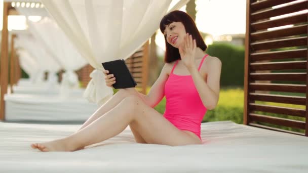 Feliz sorrindo jovem mulher, sentado em maravilhoso gazebo de madeira perto da piscina — Vídeo de Stock