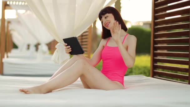 Happy smiling young woman, sitting in wonderful wooden gazebo near the pool — 비디오