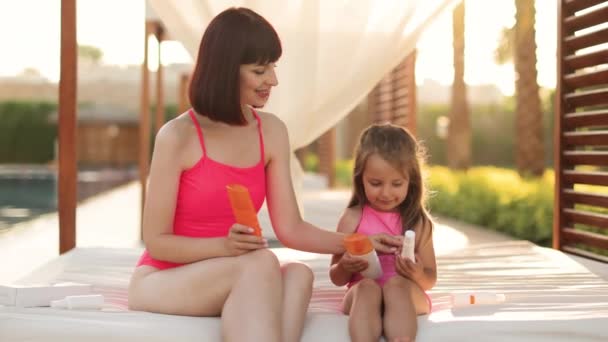 Une charmante jeune mère assise avec sa fille dans un belvédère près de la piscine — Video