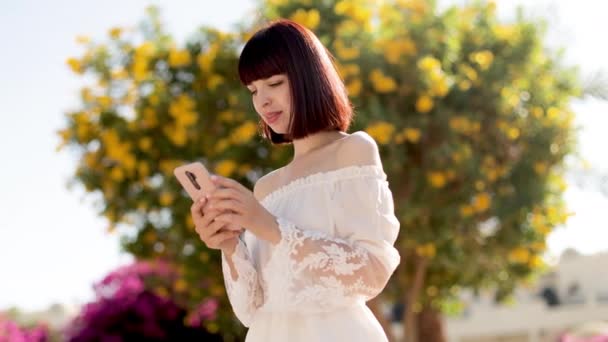 Mujer joven caucásica usando teléfono inteligente en una hermosa vista tropical en un hotel de lujo. — Vídeos de Stock