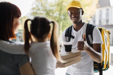 Afrikalı kurye adamdan pizza kutuları toplayan küçük tatlı bir kızla beyaz bir kadın..