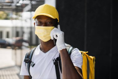 Food delivery portrait of courier african man wearing facial protective mask working during covid-19