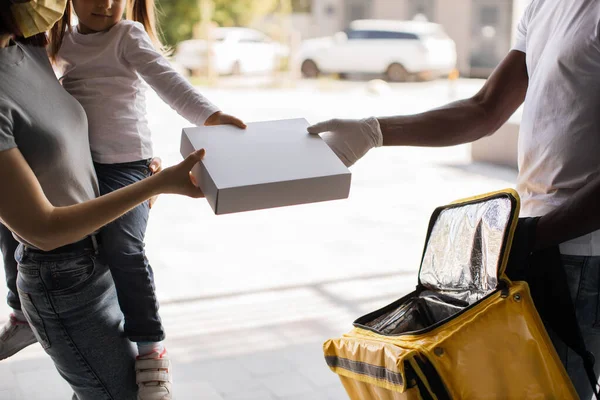 Cropped view of hands of African American courier, young female and her daughter receiving parcel — Stockfoto