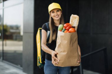 Female courier with pizza waiting for the recipient.