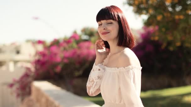 Lovely smiling lady with red hair standing on blur exotic background. — Vídeos de Stock