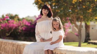 Kızıyla birlikte egzotik arka planda oturan sevimli, güler yüzlü bayan..