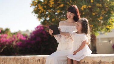 Güneşli bir günde tablet bilgisayar kullanan güzel bir anne ve küçük tatlı bir kız.