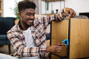 Afrikalı Amerikalı adam düz raflar için mezura kullanıyor.