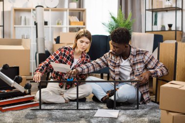 Evdeki raf boyutlarını ölçen çok ırklı genç çift.