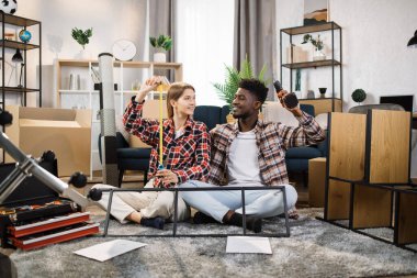 Yeni evinde elinde aletlerle mutlu bir aile.