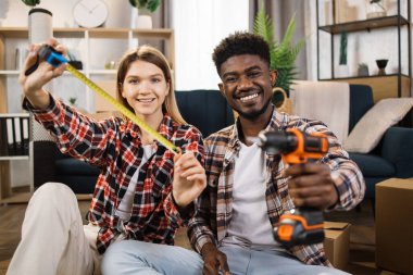 Happy family sitting on floor and holding tools