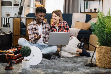 Yeni dairenin yenilenmesi için dizüstü bilgisayar kullanan çok ırklı aile.