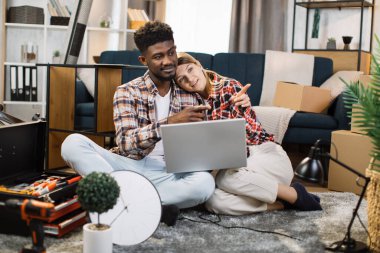 Yeni dairede dizüstü bilgisayar kullanan çok ırklı bir çift.