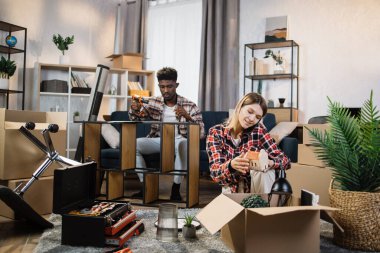 Man assembling furniture while woman talking on mobile