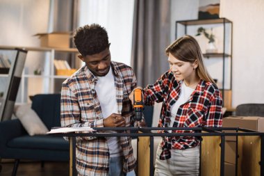 Rafları monte etmek için tornavida kullanan çok ırklı bir aile.