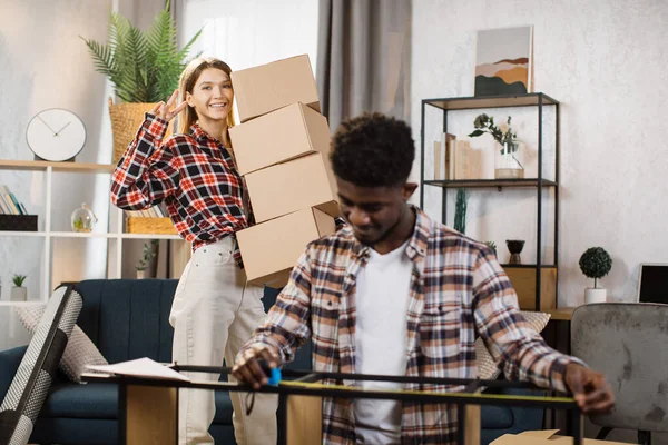 Woman holding boxes while man measuring shelves at new home — Stockfoto