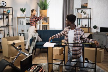 Multicultural couple unpacking boxes at new flat
