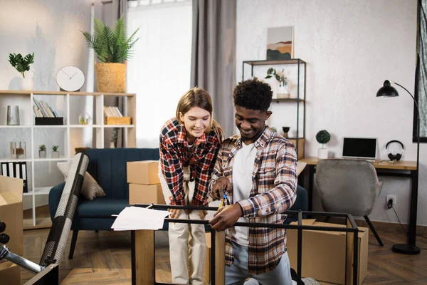 Çok ırklı bir çift evdeki kitaplığın ölçümlerini alıyor.