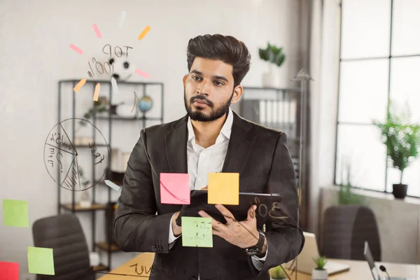 Employee looking at financial diagramm on office glass board