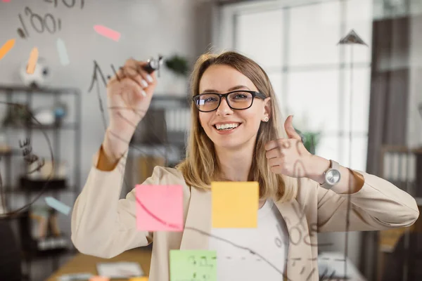 Mentor feminino mostrando o polegar para cima enquanto escreve a bordo — Fotografia de Stock