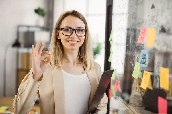 Wanita bisnis memegang papan klip dan tersenyum di kantor — Stok Foto