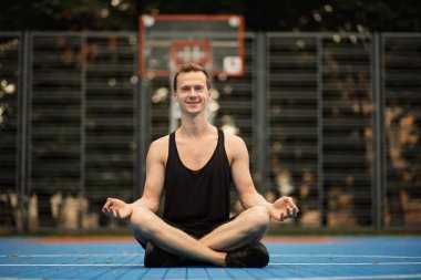 Spor salonunda egzersiz ve meditasyon yapan rahat bir adam..