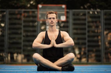 Spor salonunda egzersiz ve meditasyon yapan rahat bir adam..