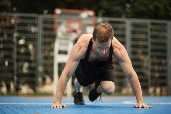 有动力的男性运动员做腹肌运动，在室外进行健美训练，站在木板上. — 图库照片