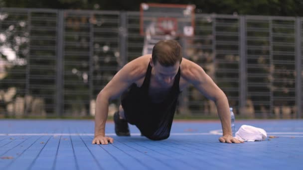 体操公園でプッシュアップを行うクロスフィット強度トレーニングに取り組んで若い白人男性に適合します 板の上に立っている男は敷物の上にポーズ フィットネス 広告の概念 — ストック動画
