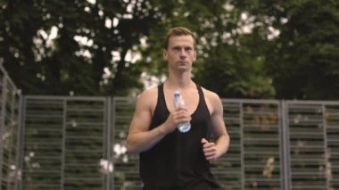 Spor kıyafetleri içinde neşeli kaslı adam sabah vakti yeşil şehir spor salonunda koşuyor. Yakışıklı beyaz adam aktif ve sağlıklı yaşam tarzları yönetiyor..