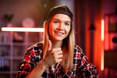 Mesafe çalışması ve öğrenme. Siyah şapkalı ve laptoplu beyaz kız öğrenci video sohbeti için evde ders çalışıyor. Masada oturan ve dizüstü bilgisayarda yazan serbest çalışan bir kadın..