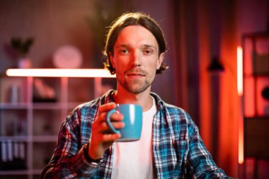 Ofiste kahve, çay ya da sıcak içecek içen kendinden emin genç bir adam. Akşamları modern ofiste ya da evde çalışan beyaz erkek işçi..