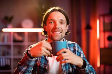 Ofiste kahve, çay ya da sıcak içecek içen kendinden emin genç bir adam. Akşamları modern ofiste ya da evde çalışan beyaz erkek işçi..