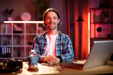 Mesafe çalışması ve öğrenme. Bilgisayarlı, video sohbeti için bilgisayarı olan genç, beyaz bir öğrenci. Evde ders çalışıyor. Masada oturan ve dizüstü bilgisayarda yazan serbest çalışan bir erkek..