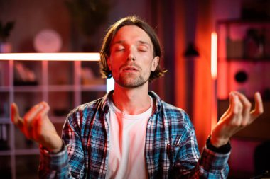 Modern laptopla masada otururken gözleri kapalı meditasyon yapan olumlu bir adam. Erkek serbest çalışan işyerindeki stresi azaltmak için yoga yapıyor. İnsan kavramı ve olumlu düşünce.