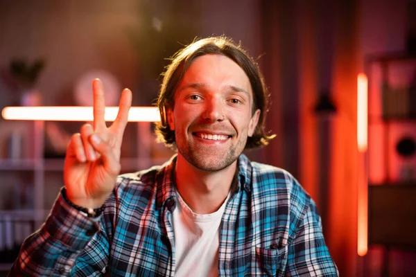 Çekici bir adam masada oturuyor, elleri göğsünde çaprazlanmış ve kameraya bakıyor. Gündelik giysiler içindeki beyaz erkek çalışma saatleri boyunca evde mola veriyor..