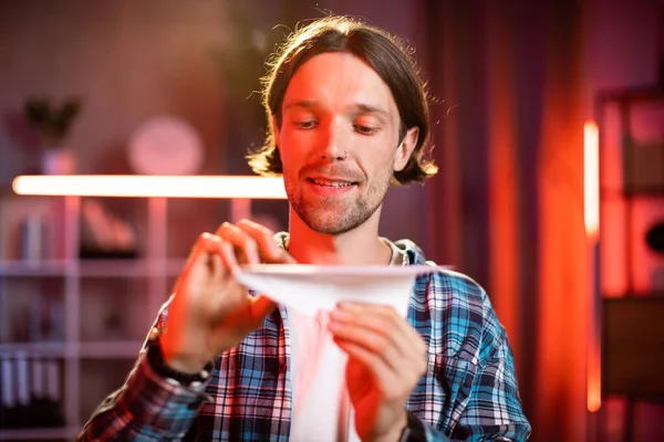 Akşamları kareli gömlekli, kağıt uçakla oynayan çekici beyaz kadın. Genç bayan serbest çalışan masa başında oturuyor ve evde işi başından savıyor..