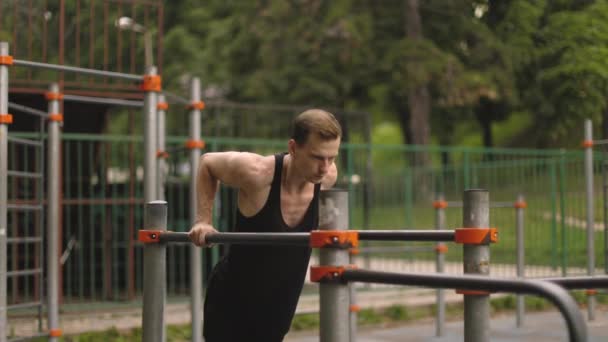 屋外で運動公園の平行棒にトリップディップを行うフィット男 美しい男は仕事をし 別の演習屋外で — ストック動画