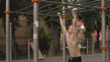 Adam, parkta mide egzersizi yapıyor. Arkadan bak. Spor kıyafetleriyle spor sahasında egzersiz yapan bir adamın seçici odak noktası..