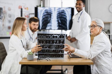 Farklı yaşlardaki uluslararası doktorlar, akciğer ve beyin röntgenlerini incelemek için toplantı odasında toplanıyorlar. Ağır hasta teşhisi ve tedavisini düşünen tıp uzmanları.