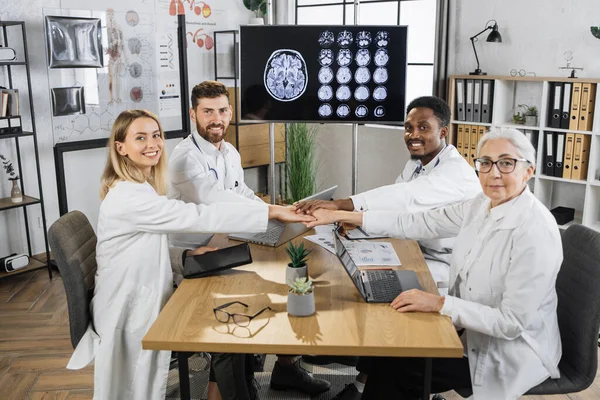 Портрет Багаторасової Групи Щасливих Лікарів Які Тримаються Руки Сидячи Столом — стокове фото