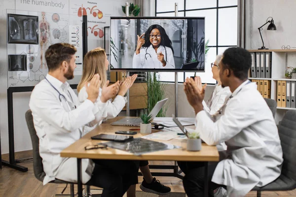 Tým Multikulturních Lékařů Bílých Laboratorních Pláštích Tleská Při Online Videokonferenci — Stock fotografie