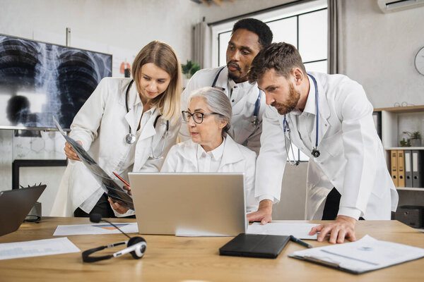 Multiethnic Physicians Discussing Ray Scan While Standing Senior Female Doctor Stock Image