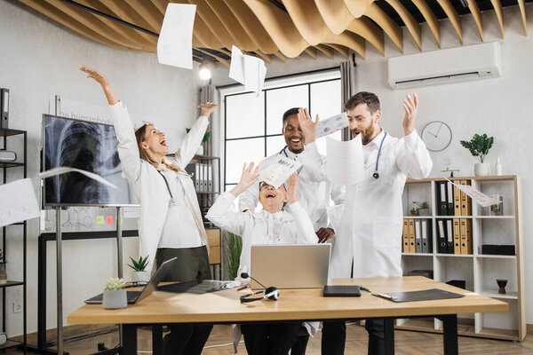 Excited Multiracial Scientists White Medical Uniform Laughing Throwing Documents Air Royalty Free Stock Photos